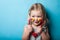 European little girl with toy stethoscope in hands on a blue background