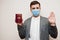 European man in formal wear and face mask, show Greece passport with stop sign hand. Coronavirus lockdown in Europe country