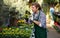 European man gardener attentively inspects calendula in pots