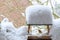 European robin  (Erithacus rubecula) with orange breast on a  wooden bird feeder in the garden after snowfall in winter