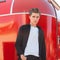 European serious young man in a stylish shirt in a white T-shirt with a trendy hairstyle poses near a vintage red trailer