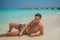 European tanned sexy man enjoying sun bathing at tropical sandy beach at island luxury resort