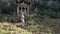 European tourist walks down hillside after visiting Lycian rock tombs in Fethiye, Turkey, in early spring.