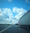 European truck vehicle on motorway with blue sky and white clouds. Cargo transportation.