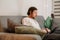 European unshaven man using laptop while resting on sofa