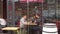 European urban population eats sitting at tables in verandas of cafes.
