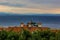 European village landmark view house shingle roof above green tree foliage foreground and Adriatic sea scenery landscape horizon