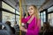 A European woman dressed in pink stands inside public transport