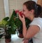 European woman sniffing flower plant at home