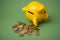 euros coins falling from yellow piggy bank on green background
