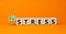 Eustress or stress symbol. Turned the wooden cube and changed the concept word Eustress to Stress. Beautiful orange table orange