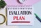 EVALUATION PLAN text written on a notebook with pencils, magnifier