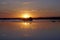 Evening in August over the lake.  Scarlet sun and water glare and reflection. Horizon.