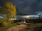 Evening countryside landscape with dramatic rain clouds and the road to the ancient palace