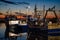 Evening fishing vessels moored at a dock under sunset sky.