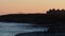 Evening: Flight of pelicans silhouetted over Natural Bridges State Beach