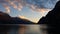 Evening landscape of mountain lake, pink clouds backlit by the setting sun