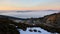 Evening landscape with tall open-cast quarry mine, pit benches and ramps clearly visible, dense fog in background.