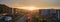 Evening panorama of the city outskirts. Hills and mountains at sunset, urban landscape and new buildings