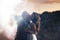 Evening photo of hugging wedding couple. Groom passionately kissing bride. Emotion in female face. Smoke effect.