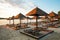 Evening sandy beach with brown wooden loungers and umbrellas