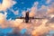 Evening sky with broken beautiful clouds of warm colors and airplane takes off from the airport