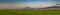 evening spring agricultural landscape. panoramic view of the hilly green field and dramatic sky after sunset