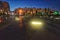 Evening square with beautiful lighting and people walking in it.