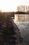 Evening sun shining on dam and concrete pier with spillway channel of larger artificial fish pond.