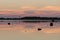 Evening sunlight, lighthouse and rocks on coast. Sky reflection on water. Beach in summer. Seaside natural environment.