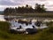 Evening sunset on the lake. Three boats on the shore. The sun sets and is reflected in the water.