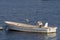 An evening sunset with a rustic looking boat absorbing the rays in the blue water.