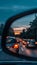 Evening traffic jam rearview mirror shows cars with headlights on, queuing in a line