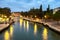 Evening view of illuminated old architecture, floating boats and light reflections in canals water in Venice, Italy