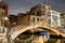 Evening view of illuminated old architecture, floating boats and light reflections in canals water in Venice, Italy