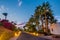 Evening view for road in illumination, white apartments, palm trees