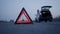 Evening view of triangle sign on roadway in front of blurred background