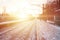 Evening winter landscape with the railway station. Snow-covered railway platform under the sun light at sunset. A place where peo