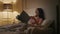 Evening woman reading novel in cozy bed. Smiling relaxed reader resting home