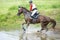 Eventing: equestrian rider jumping over an a log fence obstacle