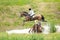 Eventing: equestrian rider jumping over an a log fence water obstacle