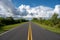 Everglades National Park road receding into distance under stormy cloudscape.