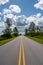 Everglades National Park road receding into distance under stormy cloudscape.