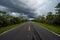 Everglades National Park road receding into distance under stormy cloudscape.