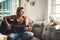 Every artist appreciates an attentive audience. a young woman playing a guitar on a relaxing day at home.