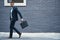 Every businessman needs a briefcase. a handsome young businessman carrying a briefcase against a grey facebrick wall.