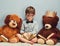 Everybody needs a cool study buddy. Studio shot of a smart little boy reading a book next to his teddy bears against a