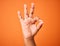 Everythings going to be just fine. Shot of an unrecognizable person showing a hand gesture against an orange background.