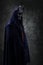 Evil cultist with dark cloak against dark background