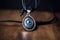 evil eye amulet, hanging from leather strap, with silver charm